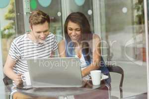 Smiling friends with chocolate cake using laptop