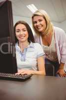Smiling teacher and student behind desk at computer