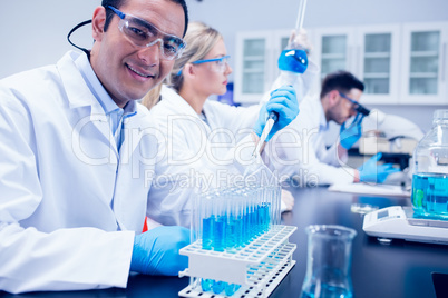 Science student using pipette in the lab to fill test tubes