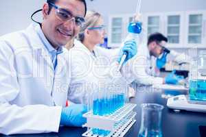 Science student using pipette in the lab to fill test tubes