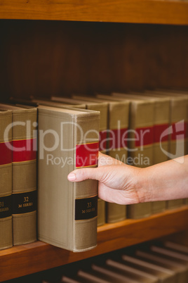 Hand taking a book from bookshelf