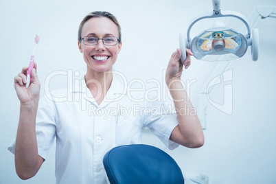 Smiling female dentist holding toothbrush