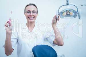 Smiling female dentist holding toothbrush