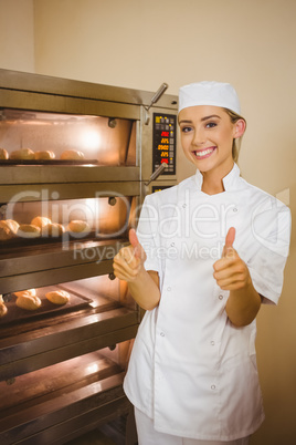 Baker smiling at camera beside oven