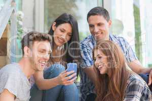 Happy students looking at smartphone outside on campus