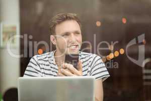 Smiling student touching his mobile phone