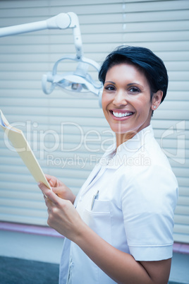 Smiling female dentist reading reports