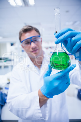 Chemist holding up beaker of green chemical