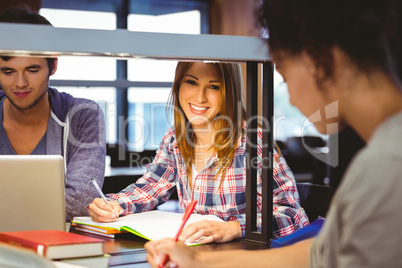 Happy student sitting at desk writing smiling at camera