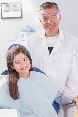 Smiling dentist with safety glasses and happy young patient
