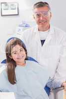 Smiling dentist with safety glasses and happy young patient