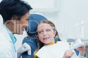 Female dentist teaching girl how to brush teeth