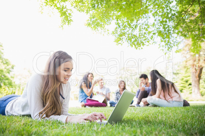 Happy student using her laptop outside