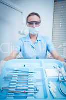 Female dentist in surgical mask holding tray of tools