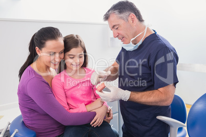 Pediatric dentist explaining to young patient and her mother the