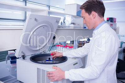 Chemist in lab coat using a centrifuge