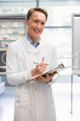 Handsome pharmacist writing on clipboard