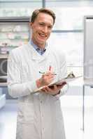 Handsome pharmacist writing on clipboard