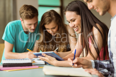 Smiling friends sitting studying and using tablet pc