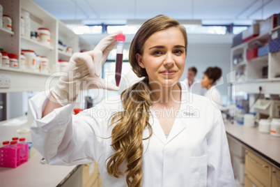 Pretty science student smiling and showing vial