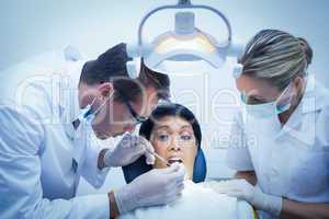 Dentist with assistant examining womans teeth