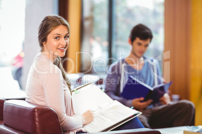 Students sitting on couch revising and smiling at camera