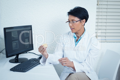 Dentist holding mouth model besides computer