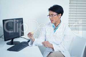 Dentist holding mouth model besides computer