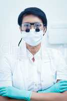 Female dentist wearing surgical mask and dental loupes