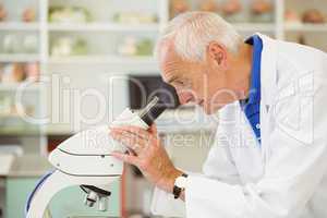 Senior scientist looking through microscope