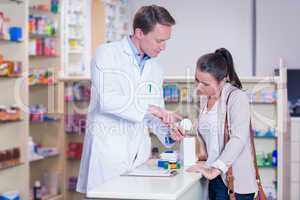 Pharmacist showing a drug box to a young woman