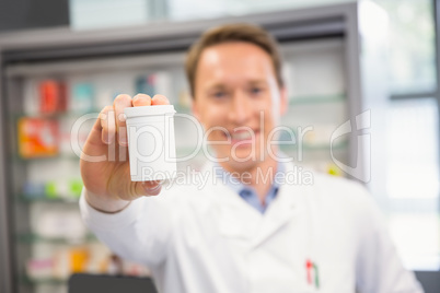 Handsome pharmacist showing medicine jar