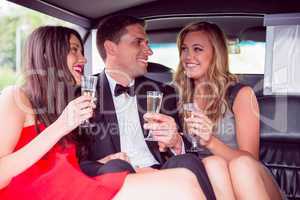 Happy friends drinking champagne in limousine