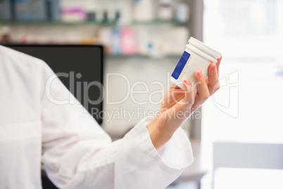 Junior pharmacist holding medicine jar