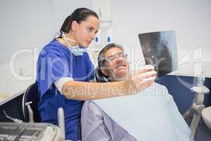 Smiling dentist showing x-ray to her patient