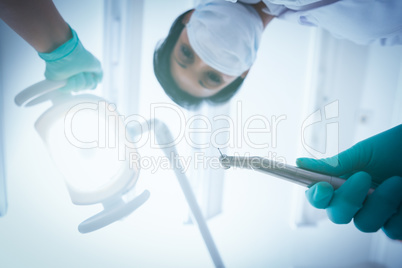 Female dentist in surgical mask holding dental drill
