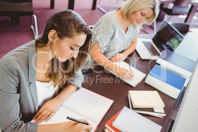 Matures females students writing notes at desk
