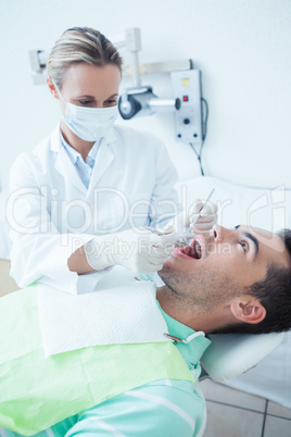 Female dentist examining mans teeth