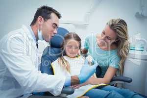 Dentist teaching girl how to brush teeth