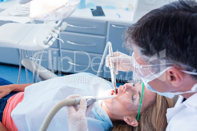 Dentist examining his patient with a suction hose