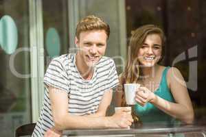 Smiling friends holding mug of coffee