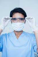 Female dentist wearing surgical mask and safety glasses