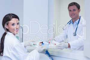 Doctor giving tray with blood sample to his colleague