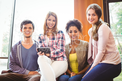 Happy students sitting on a sofa using mobile phone