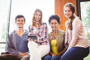 Happy students sitting on a sofa using mobile phone