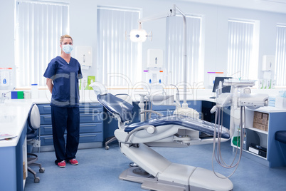 Dentist in blue scrubs standing beside chair