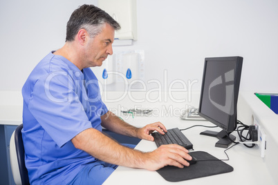 Serious dentist sitting and using computer