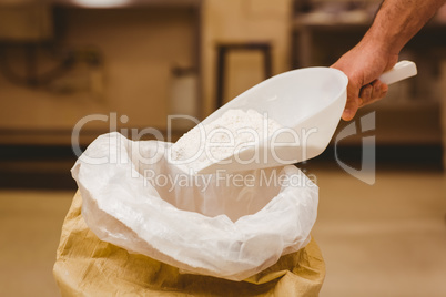 Baker scooping flour out of sack