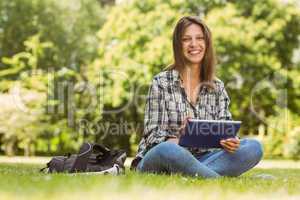 Smiling student sitting and using tablet pc