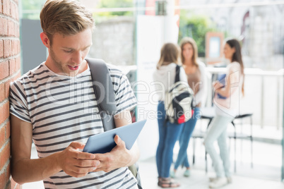 Handsome student smiling and holding tablet